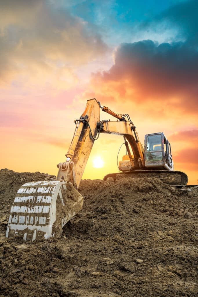 Pelle Excavatrice Chantier Terre Coucher Soleil Dramatique Pelle mécanique jaune travaillant sur un chantier de terre boueuse au coucher du soleil aux couleurs vives.