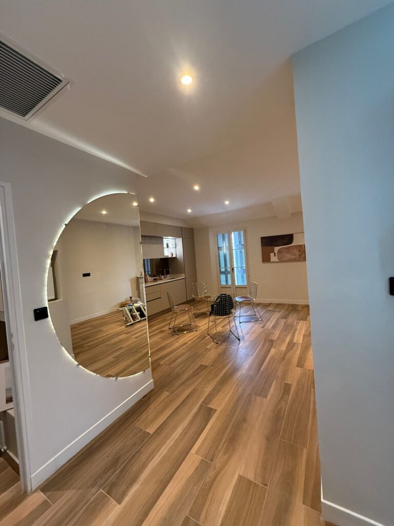 Grand miroir rond rétroéclairé dans un salon moderne avec parquet en bois et mobilier design.